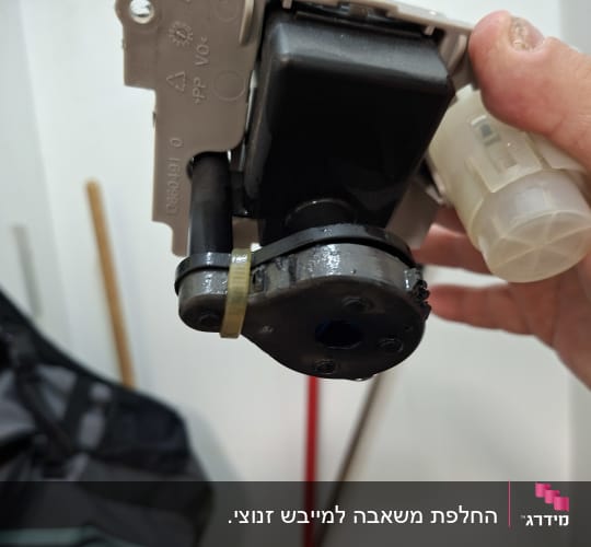 טכנאי מחזיק רכיב חשמלי פנימי במהלך תיקון מוצר חשמל